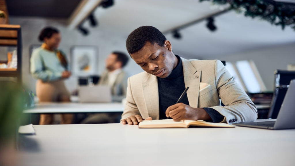 Leader taking notes during a meeting as part of continuous learning and leadership development